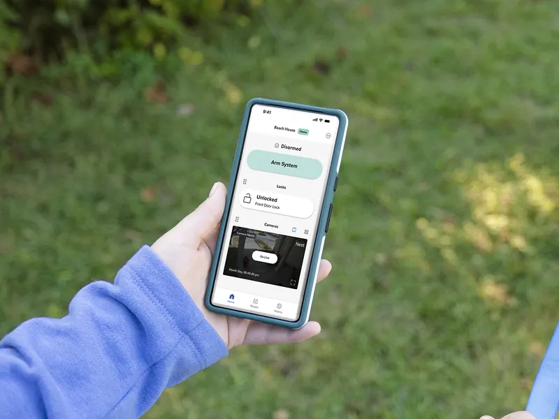 Homeowner checking the ADT+ app on a phone while walking a dog